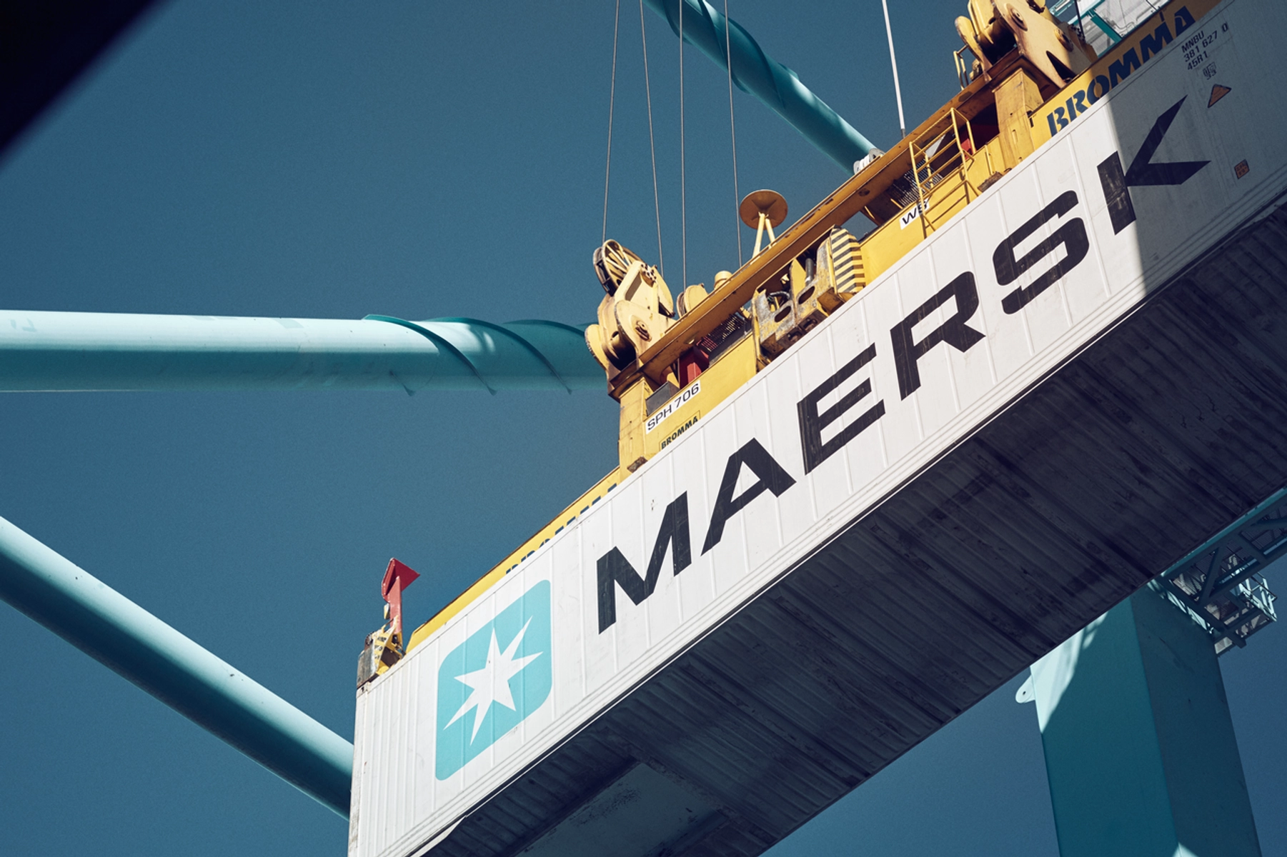 A Maersk shipping container being lifted by a crane.